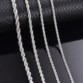Silver rope chains on a textured black surface, reflecting light and showing intricate details.